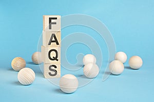 pyramid of wooden cubes with the word FAQS and wooden balls on a blue background