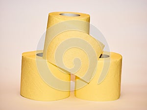 Pyramid of yellow toilet paper over white background