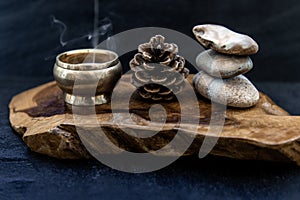 Pyramid of zen stones, Pine cones and Burning candle on old wooden background, Meditation concept, dark toned style