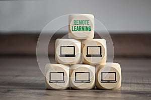 Pyramide made of cubes or dice with computer icons and Remote Learning on a wooden background