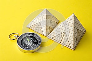 Pyramids and compass on yellow background