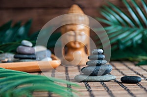 Pyramids of gray zen stones with green leaves and Buddha statue. Concept of harmony, balance and meditation, spa, massage, relax