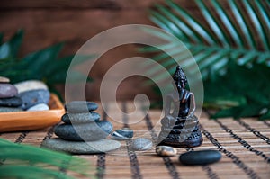 Pyramids of grey zen stones with green leaves and Buddha statue. Concept of harmony, balance and meditation, spa, massage, relax