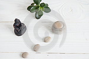 Pyramids of white zen stones with green leaves and Buddha statue. Concept of harmony, balance and meditation, spa, massage, relax