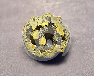 Pyritized geode of quartz on a gray background