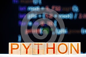 Python concept. wooden blocks with python inscription and program code on the background.