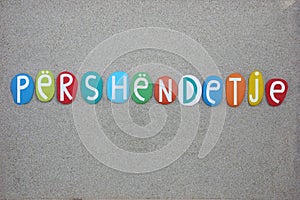 Përshëndetje, albanian word meaning hello composed with multi colored stone letters over beach sand