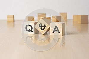 Q and A - an abbreviation of wooden blocks with letters on a gray background. reflection caption on the mirrored surface