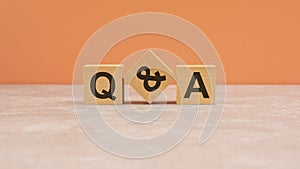 Q and A - acronym from wooden blocks with letters, questions and answers concept. orange background. copy space