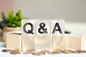 Q AND A concept with wooden blocks and coins on table  business concept. Q AND A - question and answer