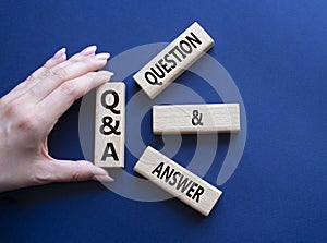 Q and A - Question and Answer. Wooden cubes with words Q and A. Businessman hand. Beautiful deep blue background. Business and Q