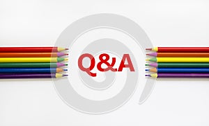 Q and A symbol. Concept word `Q and A, questions and answers` on a beautiful white background. Colored pencils. Business and Q a
