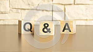 Q and A text from wooden blocks on a gray stone background. QA is short for Question and Answer information concepts