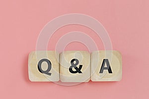 Q and A text on wooden cube block pink background. word question answer symbol.