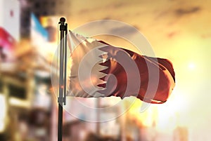 Qatar Flag Against City Blurred Background At Sunrise Backlight