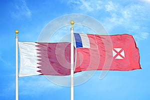 Qatar and Wallis and Futuna two flags on flagpoles and blue cloudy sky