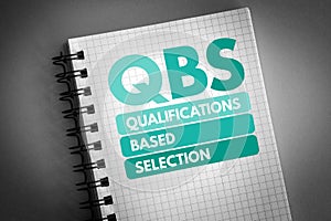 QBS - Qualifications Based Selection acronym on notepad, business concept background