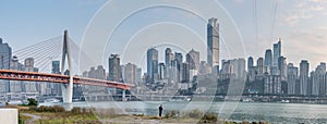 Qian si men suspension bridge over Jialing river, with man on river bank, view from river in Chongqing, southwest China