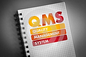 QMS - Quality Management System acronym on notepad, business concept background
