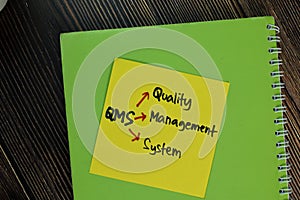 QMS - Quality Management System write on sticky notes isolated on Wooden Table