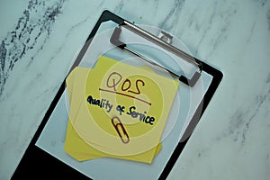 QOS - Quality of Service write on sticky note isolated on Wooden Table. Business Concept photo