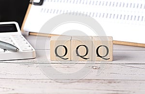 QQQ word on a wooden block with clipboard and calcuator