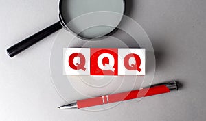 QQQ word on wooden cubes with pen and magnifier