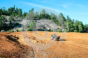 Quad ATV stands on sandy terrain at a beautiful lake.