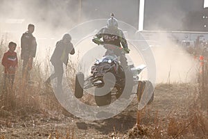 Quad Bike airborne over hump in trail of dust on sand track duri