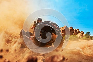 Quad bike rider climbing the sands, front view