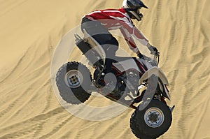 Quad bike rider in mid-air over sand