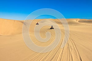 Quad driving people - two happy bikers in sand desert.