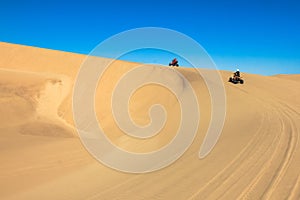 Quad driving people - two happy bikers in sand desert.