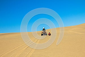 Quad driving people - two happy bikers in sand desert dunes, Africa, Namibia, Namib, Walvis Bay, Swakopmund.