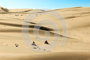 Quad driving people - two happy bikers in sand desert dunes, Africa, Namibia, Namib, Walvis Bay, Swakopmund.