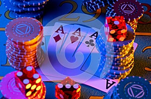 A quad of four aces, set of colored chips and dice on gaming table in casino. Playing cards, poker chips and red dice