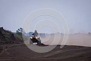 The quad racer is riding on the dirt road. Quad bike off-road. Quad bike in action