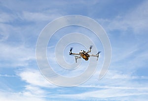 Quadcopter drone with digital camera in flight with blue sky background