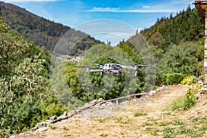 Quadcopter drone with digital camera in flight with landscape and blue sky background