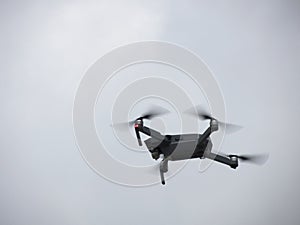 Quadcopter drone flying overhead in cloudy sky