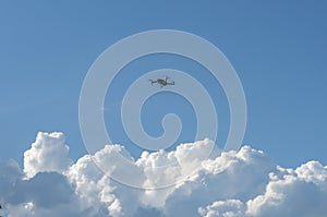 The quadcopter hovered above the clouds against the blue sky