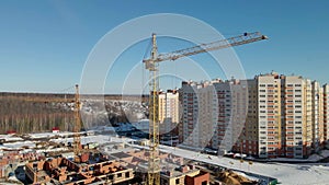 The quadcopter rises up along the construction crane. Construction site in winter.