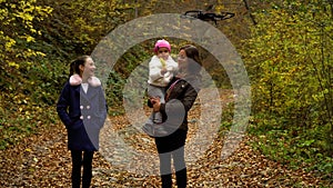 Quadcopter shoots a happy family. A young mother with her two children walks through the autumn forest. They walk along