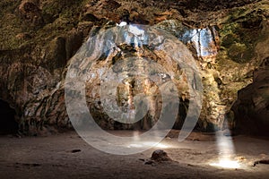 Quadiriki cave in Aruba. Sunbeams extend from cavern roof to the floor.