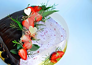 A quadrant cake, half of which is covered diagonally with chocolate and the other half with cream decorated with pieces of strawbe