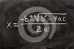Quadratic equations handwritten on a blackboard with chalk