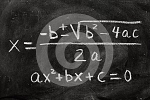 Quadratic equations handwritten on a blackboard with chalk