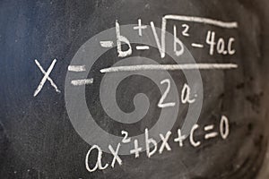 Quadratic equations handwritten on a blackboard with chalk