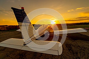 Quadruple aircraft parked at a private airfield. Rear view of a plane with a propeller on a sunset background.