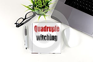 QUADRUPLE WITCHING text on notebook with laptop, mouse and pen